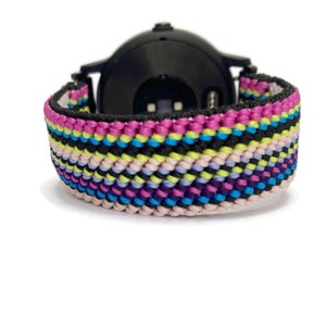 May include: A colorful woven watch band with pink, blue, green, black, and white stripes. The band is made of a soft, flexible material and is designed to fit most smartwatches.