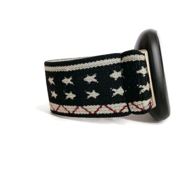 May include: A black and white patterned elastic band with white stars and red stitching. The band is attached to a black plastic object.