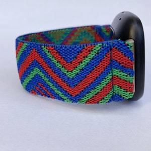 May include: A black fitness tracker with a colorful chevron patterned elastic band. The band is red, green, and blue.