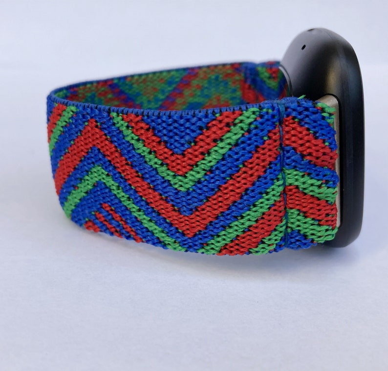 May include: A black fitness tracker with a colorful chevron patterned elastic band. The band is red, green, and blue.