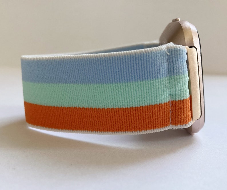 May include: A striped watch band with blue, green, and orange stripes. The band is made of a soft, stretchy material and is compatible with smartwatches.