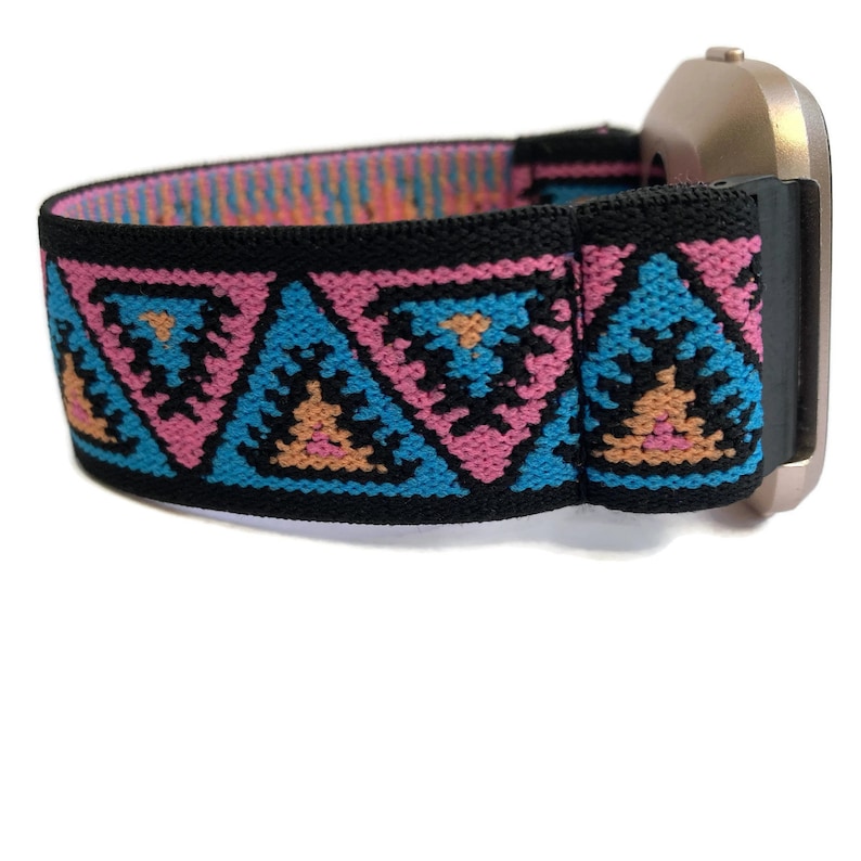 May include: A black elastic watch band with a geometric pattern in pink, blue, and orange. The band is attached to a silver watch face.