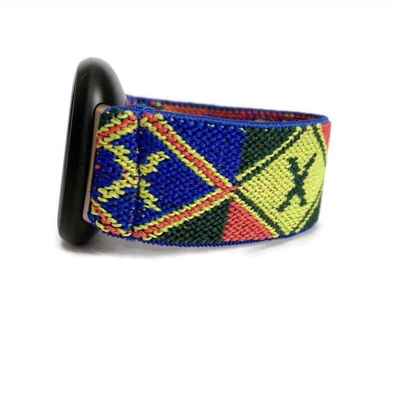 May include: A colorful woven watch band with a geometric pattern in shades of blue, green, yellow, and red. The band has a black watch face attached to it.