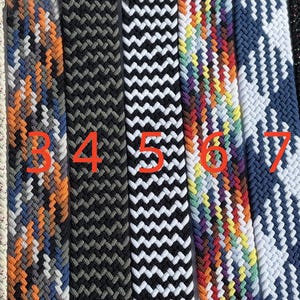 Könnte beinhalten: Eine Sammlung von neun geflochtenen Gürteln in verschiedenen Farben und Mustern. Die Gürtel umfassen Blau, Beige, Orange, Schwarz, Weiß, Regenbogen, Marine, schwarzen Glitzer und Grün. Jeder Gürtel hat ein einzigartiges Webdesign.