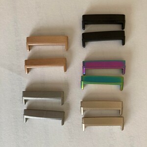 May include: Set of eight metal watch band strap connectors in various colors, including black, gold, silver, and iridescent.