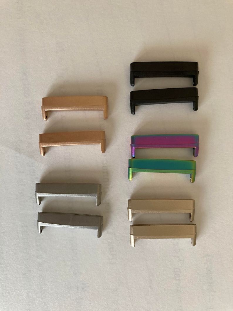 May include: Set of eight metal watch band strap connectors in various colors, including black, gold, silver, and iridescent.