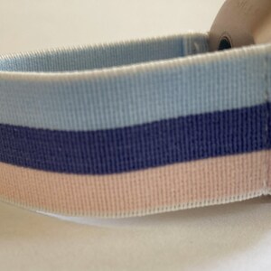 May include: A light blue, navy blue and pink striped watch strap.