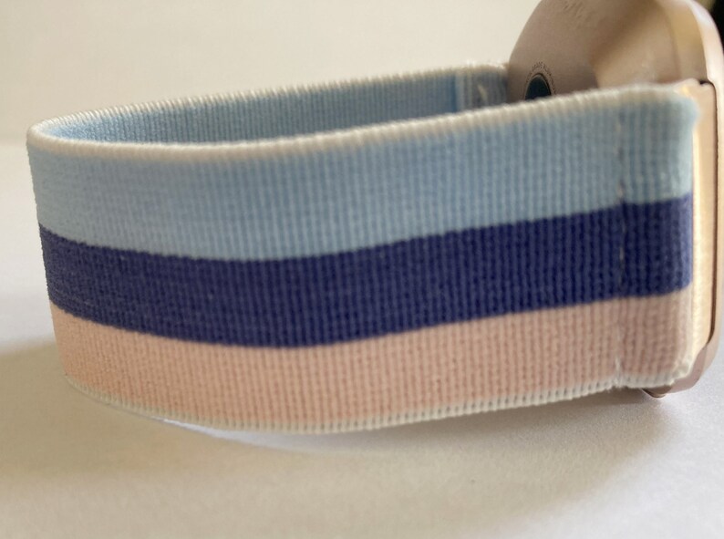 May include: A light blue, navy blue and pink striped watch strap.