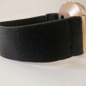 May include: A black elastic watch band with a rose gold watch face.