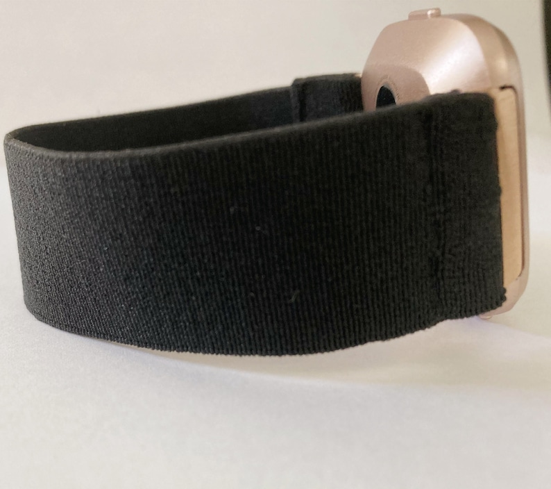 May include: A black elastic watch band with a rose gold watch face.