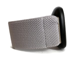 May include: A gray fabric watch band with a black circular watch face.