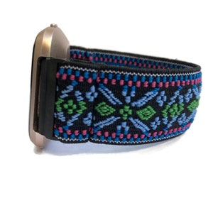 May include: A black watch band with a colorful geometric pattern. The band is made of elastic material and has a black buckle.