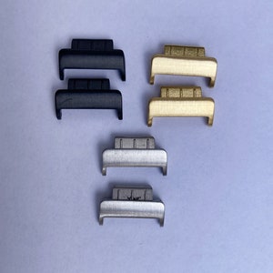 May include: Three pairs of watch band spring bars in black, gold, and silver.