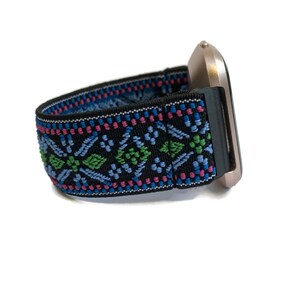 May include: A black and blue patterned watch band with a gold watch face.