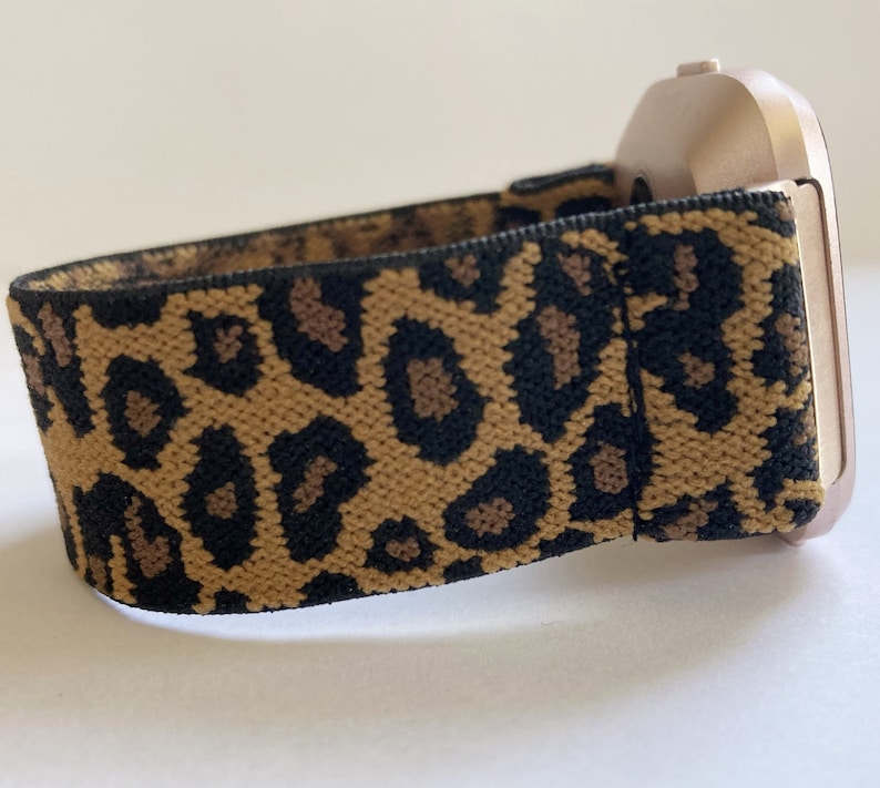 May include: A gold-colored smartwatch with a leopard print elastic band.