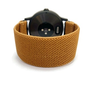 May include: A brown elastic watch band with a black watch face.