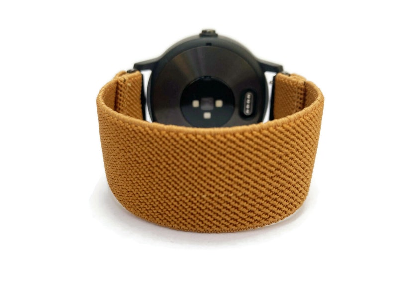 May include: A brown elastic watch band with a black watch face.