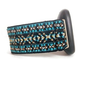 May include: A black watch band with a turquoise, brown, and white geometric pattern.