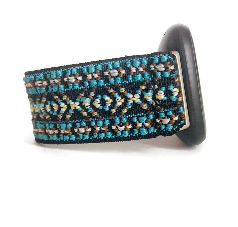 May include: A black watch band with a turquoise, brown, and white geometric pattern.