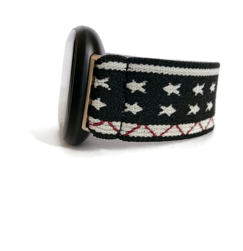 May include: A black smartwatch with a white and black patterned elastic band. The band has a red and white geometric design.