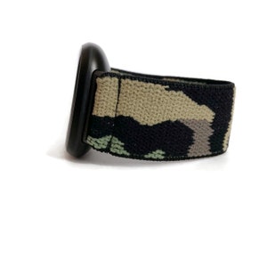 May include: A black watch band with a camouflage pattern. The band is made of a stretchy material and has a black buckle.