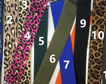 May include: A collection of watch bands in various colors and patterns. Designs include a blue and white geometric pattern, leopard print, solid colors like green, orange, blue, and black, and a gray band. These bands are designed to fit smartwatches.