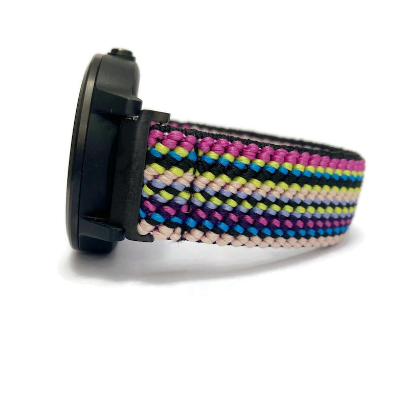 May include: A black watch with a multi-colored woven nylon strap. The strap features pink, blue, yellow, and black stripes.