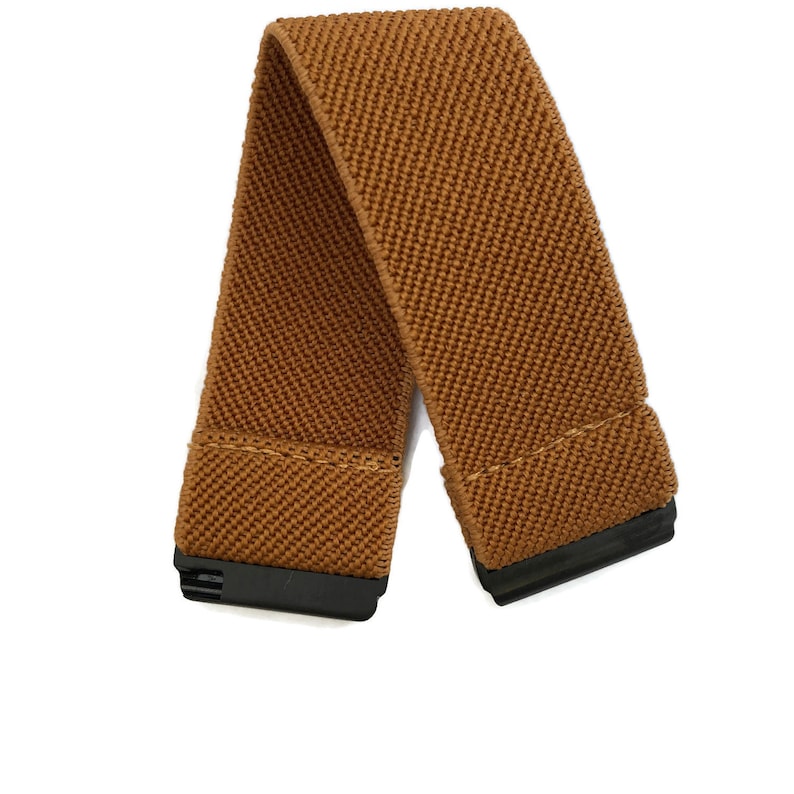 May include: A brown elastic belt with black plastic buckles. The belt is made of a woven fabric.