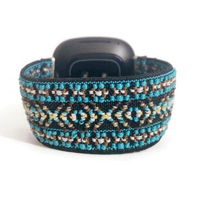May include: A black and blue patterned watch band with a geometric design. The band is made of a soft, stretchy material.