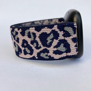 May include: A navy blue and pink leopard print watch band. The band is made of a stretchy material and is designed to fit a smartwatch.