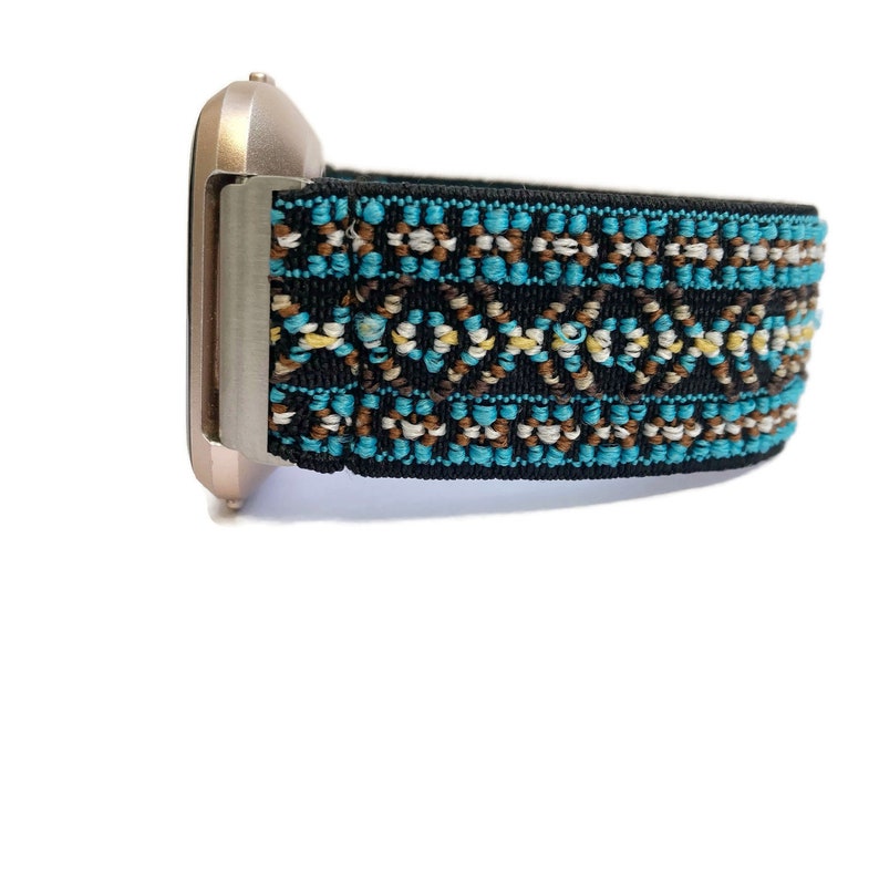 May include: A rose gold smartwatch with a black and blue patterned band. The band has a geometric design with brown, white, and blue accents.