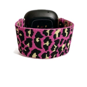 May include: A pink and black leopard print elastic watch band for a fitness tracker.