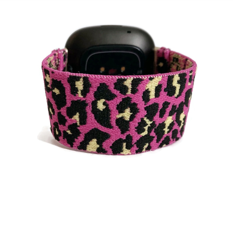 May include: A pink and black leopard print elastic watch band for a fitness tracker.