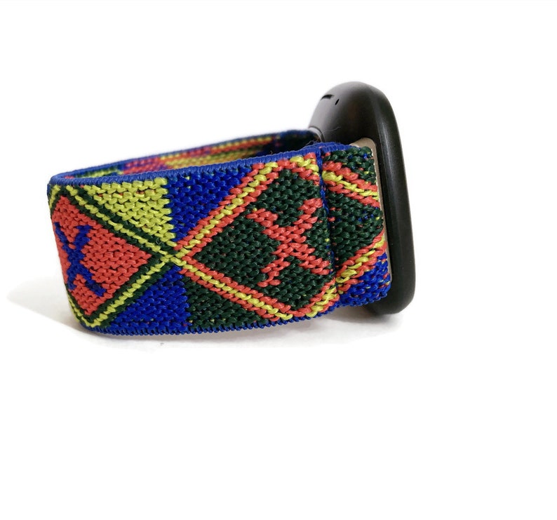 May include: A black watch with a colorful patterned strap. The strap is made of woven fabric and features a geometric design in shades of red, yellow, blue, and green.