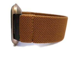 May include: A brown elastic watch band with a silver watch face.