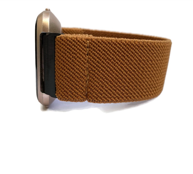 May include: A brown elastic watch band with a silver watch face.