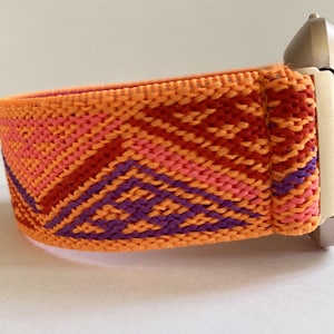 Peut inclure: Bracelet de montre à motif géométrique orange, rose, rouge et violet. Le bracelet est fait d'un matériau doux et extensible.