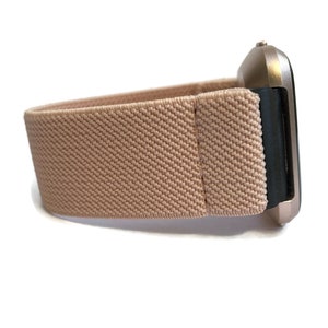 K&ouml;nnte beinhalten: Ein hellbraunes elastisches Armband mit einem goldfarbenen Zifferblatt.