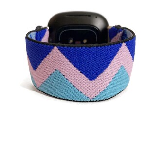 May include: An elastic watch band with a chevron pattern in blue, pink and light blue.