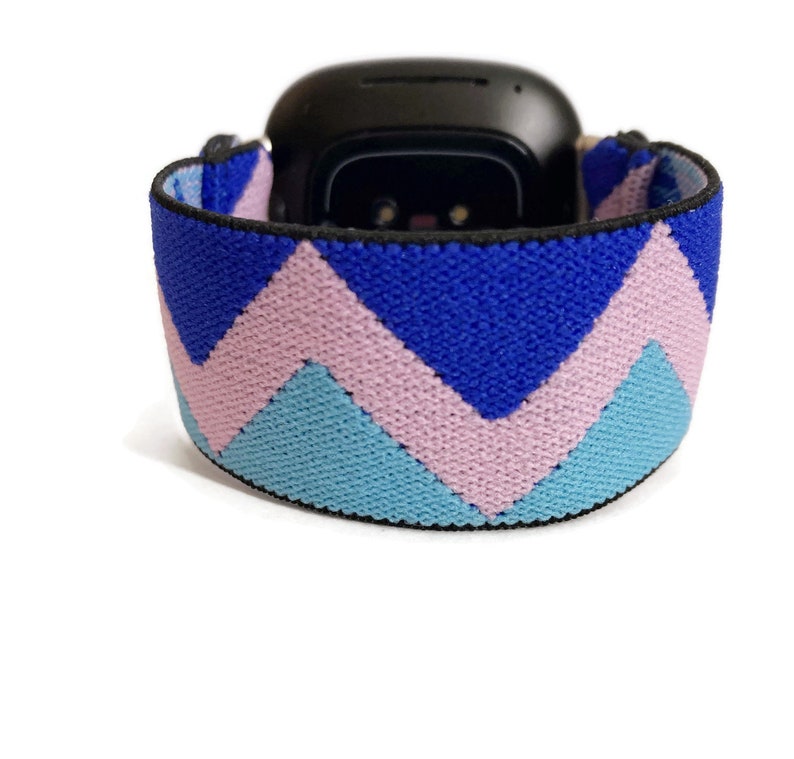 May include: An elastic watch band with a chevron pattern in blue, pink and light blue.