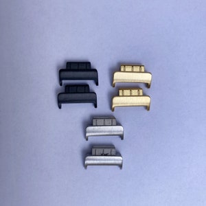 Op de afbeelding: Drie paar horlogebandconnectoren in zwart, goud en zilver. Elke connector heeft een rechthoekige vorm met een licht gebogen boven- en onderkant.