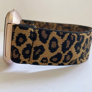 May include: A rose gold smartwatch with a leopard print elastic band.