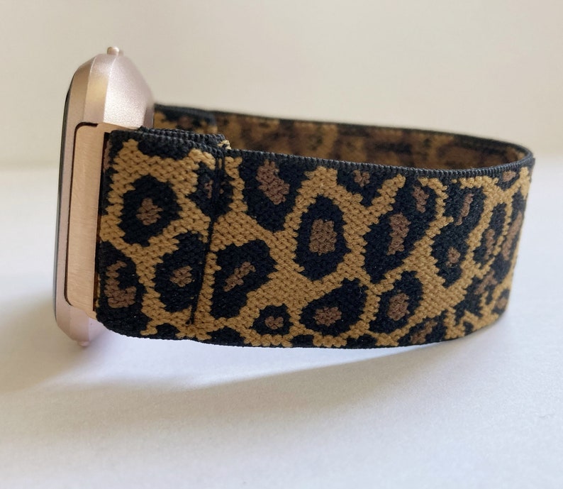 May include: A rose gold smartwatch with a leopard print elastic band.