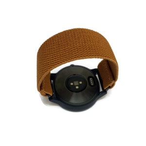 May include: A brown elastic watch band for a smartwatch. The band is made of a soft, stretchy material and has a textured surface.