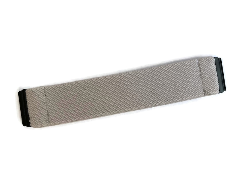 May include: A gray elastic watch band with black metal clasps.
