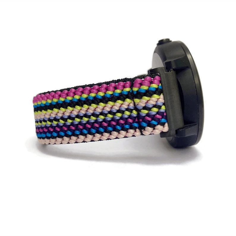 May include: A black smartwatch with a colorful striped nylon watch band. The band has pink, blue, yellow, and green stripes.