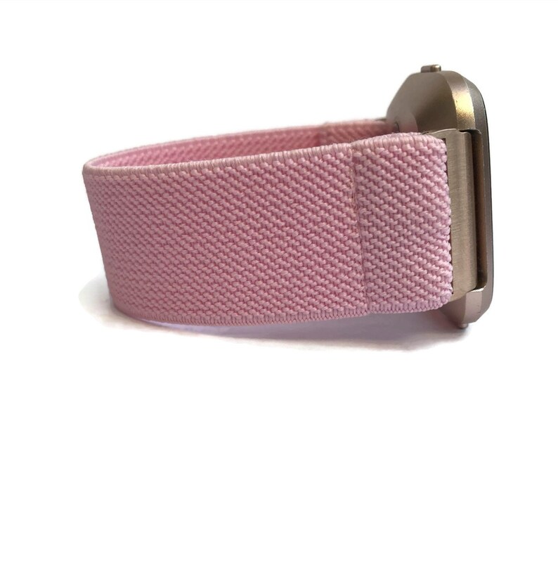 May include: A pink elastic watch strap with a silver watch face.