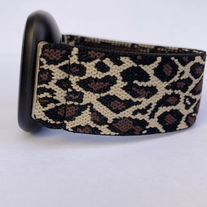Puede incluir: Una correa de reloj negra con una correa el&aacute;stica de estampado de leopardo.