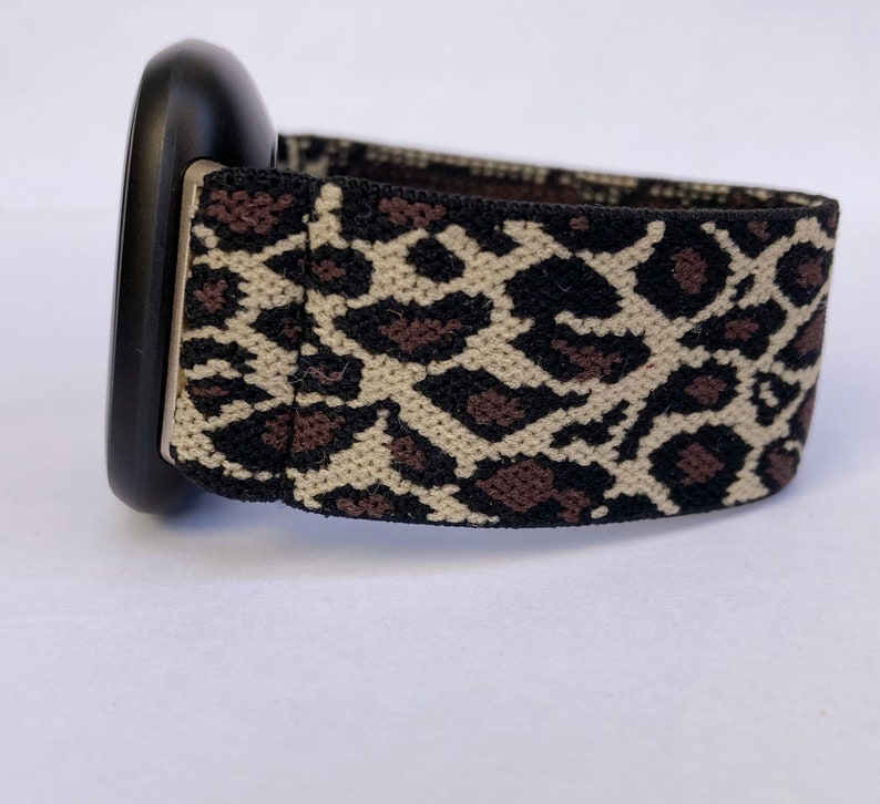 Puede incluir: Una correa de reloj negra con una correa el&aacute;stica de estampado de leopardo.