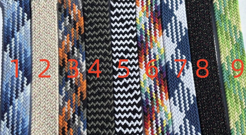 Pu&ograve; includere: Una collezione di nove cinture intrecciate in vari colori e motivi. Le cinture includono blu, beige, arancione, nero, bianco, arcobaleno, blu navy, glitter neri e verde. Ogni cintura ha un design intrecciato unico.